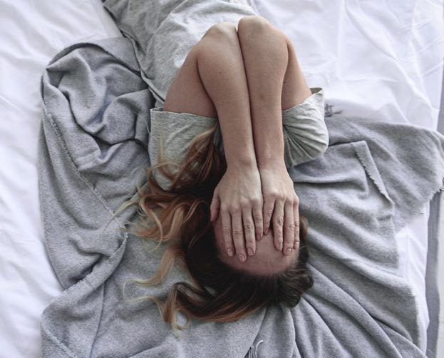 Woman suffering from psychosomatic pain laying in bed