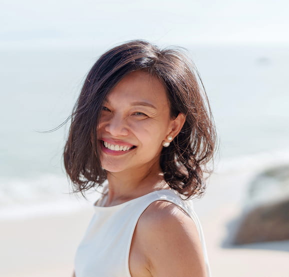 Smiling woman in a white top at the beach